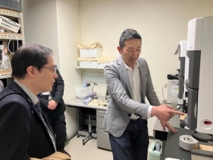 本学教員から説明を受ける松尾氏（左）